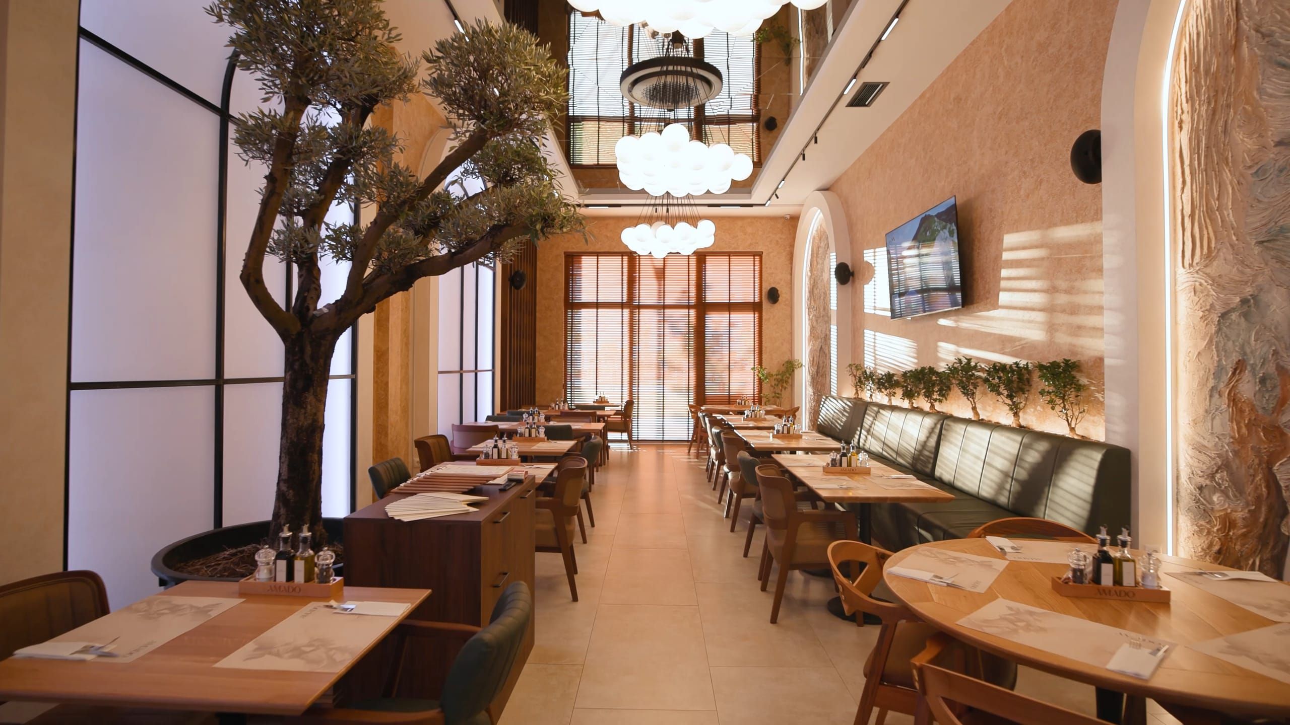 Sala restorana Amado — stablo masline, lusteri od staklenih kugli i niz drvenih stolova