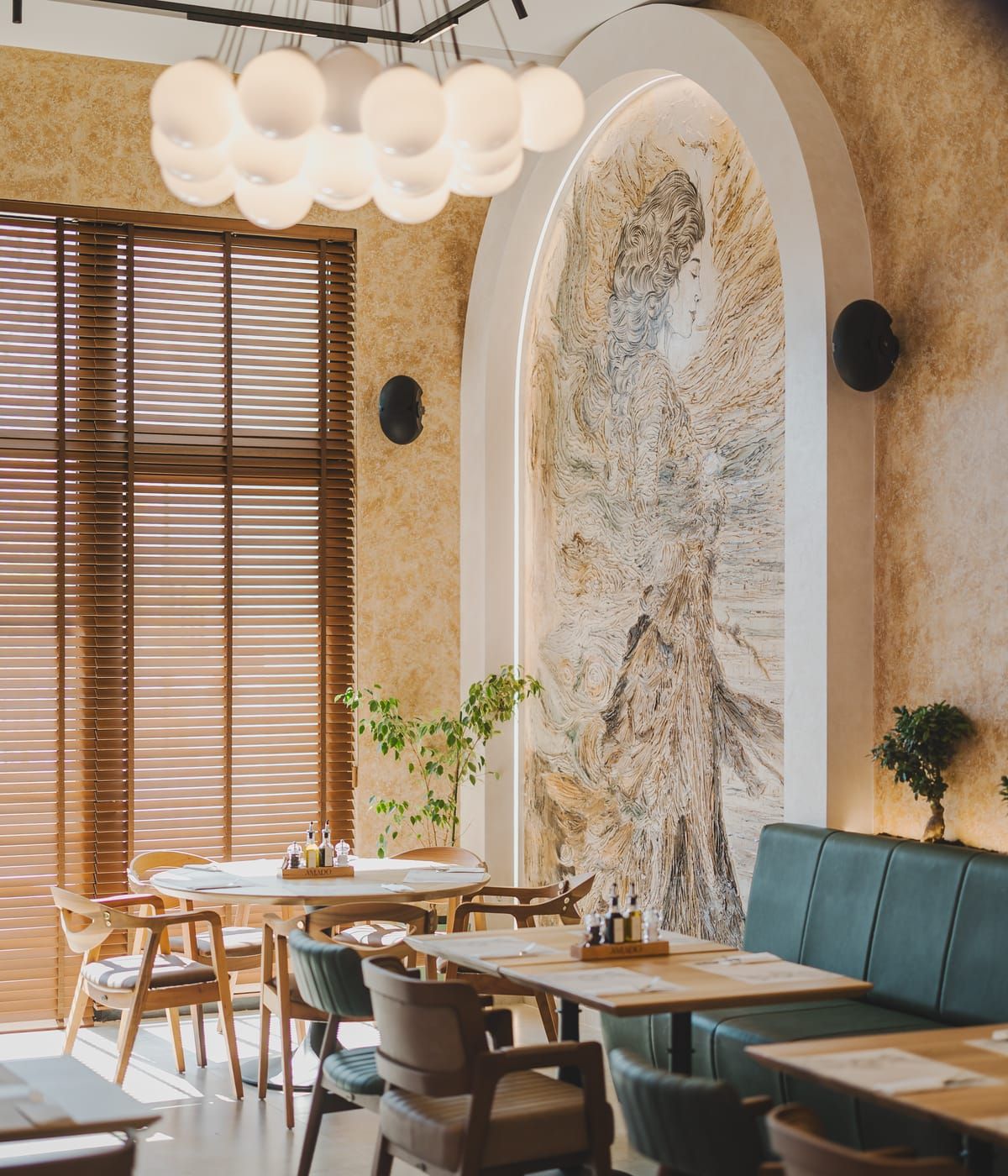 Sala restorana Amado sa drvenim stolovima i zelenim baršunastim sjedištima